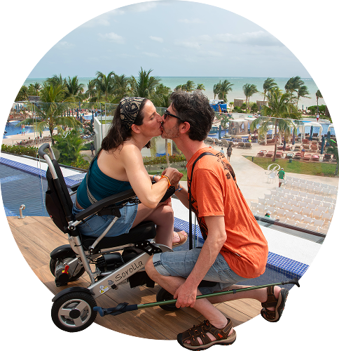 Persona usuaria de scooter eléctrico disfrutando de vacaciones junto a su acompañante en un entorno accesible